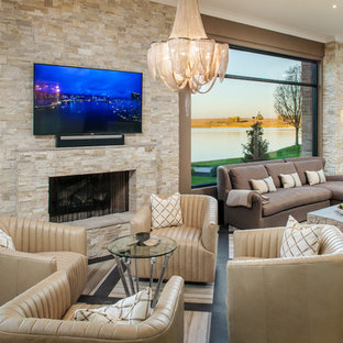 Family room - large transitional open concept porcelain tile and beige floor family room idea in Omaha with brown walls, a standard fireplace, a stone fireplace and a wall-mounted tv