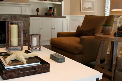 Modelo de sala de estar abierta clásica de tamaño medio con paredes beige, suelo de madera en tonos medios, todas las chimeneas, marco de chimenea de piedra y televisor colgado en la pared