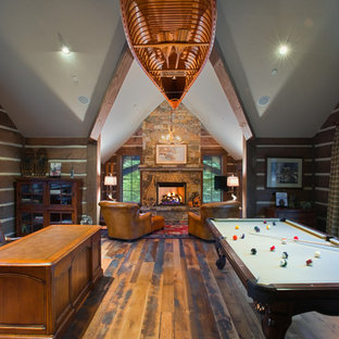Imagen de sala de juegos en casa rústica, de tamaño medio, con paredes marrones, suelo de madera oscura, chimenea tradicional, marco de chimenea de piedra y televisor colgado en la pared