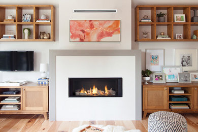 Imagen de sala de estar moderna con paredes blancas, suelo de madera clara, chimenea lineal, marco de chimenea de yeso y televisor colgado en la pared