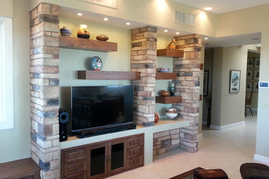 Example of a mid-sized mountain style enclosed travertine floor and beige floor family room design in Phoenix with green walls, a tv stand and no fireplace