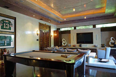 Imagen de sala de juegos en casa abierta tradicional grande sin chimenea con paredes beige, suelo de madera oscura, televisor colgado en la pared y suelo marrón