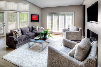 Modelo de sala de estar abierta tradicional renovada con paredes beige, suelo de madera clara y pared multimedia