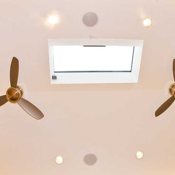 vaulted ceiling with two fans and a skylight