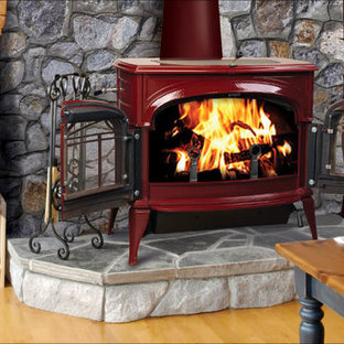 Mittelgroßes Uriges Wohnzimmer mit hellem Holzboden, Kaminofen, Kaminumrandung aus Metall, freistehendem TV, braunem Boden und schwarzer Wandfarbe in Orange County
