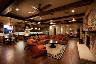 Family room - large mediterranean open concept dark wood floor and brown floor family room idea in Las Vegas with beige walls, a standard fireplace and a stone fireplace