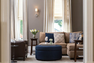 Imagen de sala de estar con biblioteca abierta clásica grande sin chimenea y televisor con paredes marrones, moqueta y suelo beige