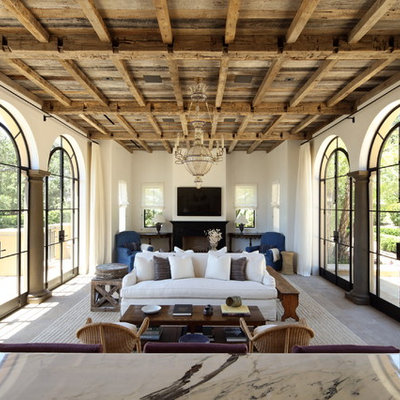 Example of a tuscan family room design in Los Angeles with white walls, a standard fireplace and a wall-mounted tv
