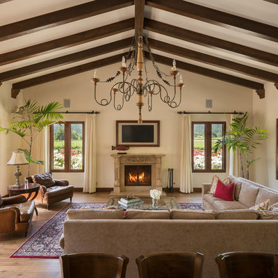 Tuscan dark wood floor and brown floor family room photo in San Francisco with beige walls and a standard fireplace