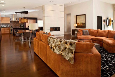 Modelo de sala de estar actual extra grande con paredes beige, suelo de madera en tonos medios, chimenea de doble cara, marco de chimenea de baldosas y/o azulejos y suelo marrón