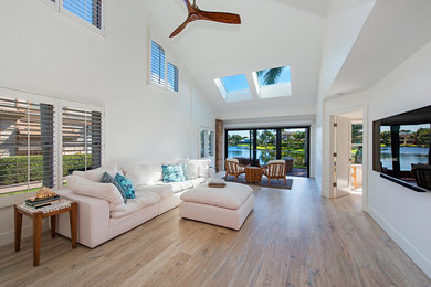 Family room - large coastal loft-style light wood floor family room idea in Tampa with white walls and a wall-mounted tv