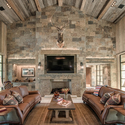 Example of a mountain style family room design in Dallas with brown walls, a standard fireplace, a stone fireplace and a wall-mounted tv