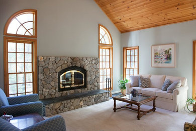 Foto de sala de estar abierta clásica de tamaño medio sin televisor con paredes grises, moqueta, estufa de leña, marco de chimenea de piedra y suelo beige