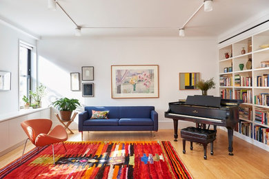 Trendy light wood floor and brown floor living room photo in New York with a music area and white walls