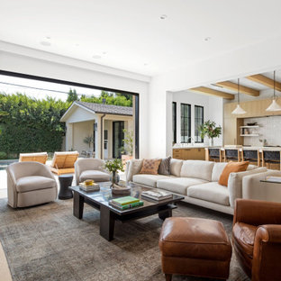 Großes, Offenes Klassisches Wohnzimmer mit weißer Wandfarbe, hellem Holzboden, Kamin, Kaminumrandung aus Stein, Wand-TV, beigem Boden und Kassettendecke in Los Angeles