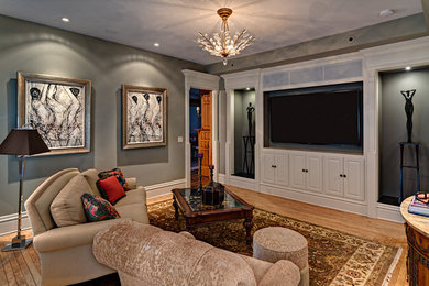 Ejemplo de sala de juegos en casa cerrada clásica renovada grande con paredes grises, suelo de madera clara y pared multimedia