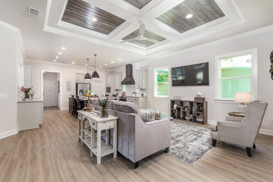 Diseño de sala de estar abierta y abovedada con paredes grises, suelo de madera clara, televisor colgado en la pared y suelo beige