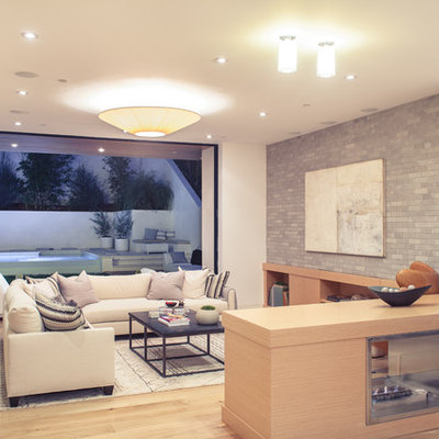 Example of a large trendy enclosed medium tone wood floor family room library design in Los Angeles with white walls, a two-sided fireplace, a wood fireplace surround and a wall-mounted tv
