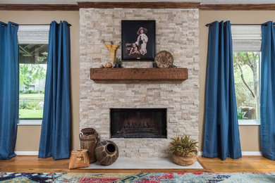ダラスにある高級な広いサンタフェスタイルのおしゃれなオープンリビング (ベージュの壁、淡色無垢フローリング、標準型暖炉、石材の暖炉まわり、茶色い床) の写真