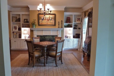 Example of a mid-sized transitional enclosed medium tone wood floor family room library design in Charlotte with brown walls, a standard fireplace, a wood fireplace surround and no tv