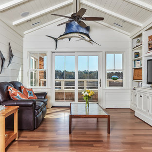 Beach style enclosed medium tone wood floor and brown floor family room photo in Atlanta with white walls, no fireplace and a media wall