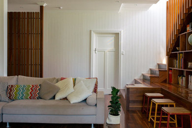 Immagine di un soggiorno contemporaneo aperto con libreria, pareti bianche, pavimento in legno massello medio e nessun camino