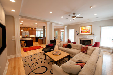 Imagen de sala de estar abierta tradicional renovada grande con paredes beige, suelo de madera clara y pared multimedia