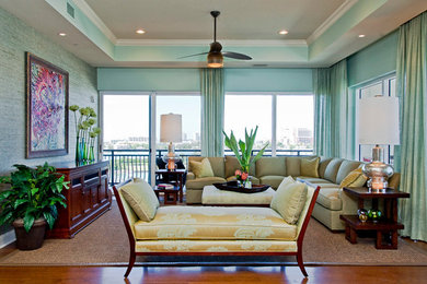 Foto de sala de estar abierta exótica grande sin chimenea con paredes verdes, suelo de madera en tonos medios y televisor retractable