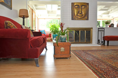 Стильный дизайн: открытая гостиная комната среднего размера в стиле фьюжн с белыми стенами, полом из ламината, стандартным камином, фасадом камина из кирпича и коричневым полом без телевизора - последний тренд