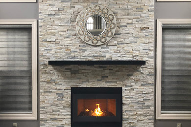 クリーブランドにあるトラディショナルスタイルのおしゃれなファミリールーム (グレーの壁、カーペット敷き、標準型暖炉、石材の暖炉まわり、グレーの床) の写真