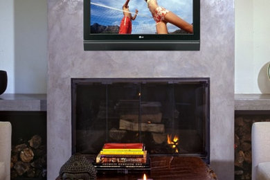 Cette photo montre une salle de séjour tendance de taille moyenne et fermée avec un mur blanc, une cheminée standard, un téléviseur fixé au mur, moquette, un manteau de cheminée en métal et un sol beige.