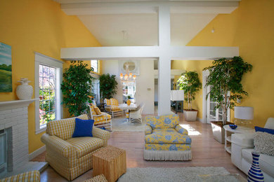Foto de sala de estar abierta tradicional renovada grande sin televisor con paredes amarillas, suelo de madera clara, todas las chimeneas y marco de chimenea de ladrillo