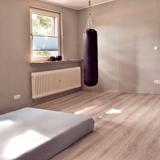 Esempio di una palestra multiuso industriale di medie dimensioni con pareti grigie, pavimento in laminato, pavimento grigio e soffitto in carta da parati