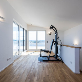 Idee per una palestra multiuso moderna di medie dimensioni con pareti bianche e pavimento in legno massello medio