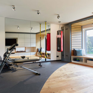 Multifunktionaler, Großer Moderner Fitnessraum mit weißer Wandfarbe, braunem Holzboden und braunem Boden in Frankfurt am Main