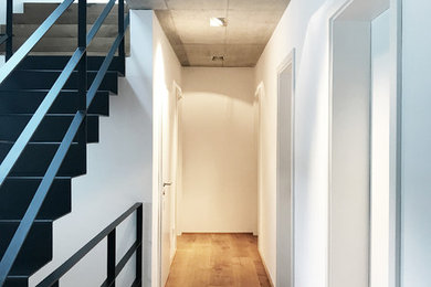 Moderner Flur mit weißer Wandfarbe, braunem Holzboden und braunem Boden in Dortmund