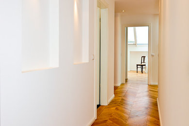 Kleiner Moderner Flur mit weißer Wandfarbe und braunem Holzboden in Hamburg