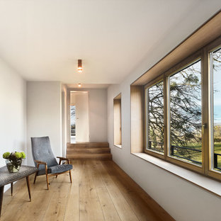 Großer Moderner Flur mit weißer Wandfarbe, braunem Holzboden und braunem Boden in München