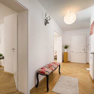Kleiner Moderner Flur mit weißer Wandfarbe, braunem Holzboden und braunem Boden in München