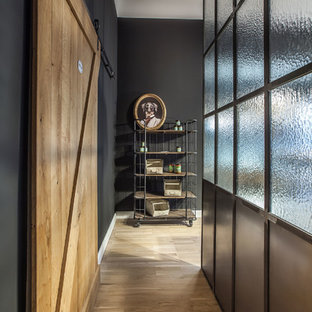 Kleiner Industrial Flur mit schwarzer Wandfarbe, braunem Holzboden und braunem Boden in Berlin