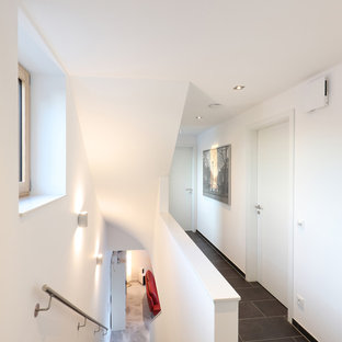 Kleiner Moderner Flur mit weißer Wandfarbe und schwarzem Boden in Sonstige
