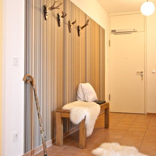 Idée de décoration pour un grand couloir design avec un mur beige, un sol en carreau de terre cuite et un sol rouge.