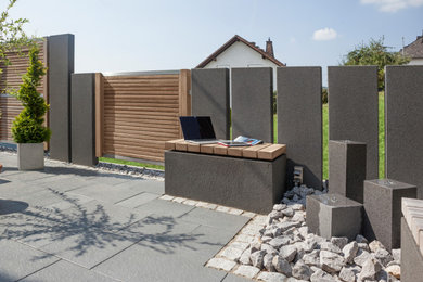 Modelo de jardín actual con muro de contención y adoquines de hormigón