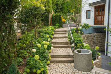 Foto de jardín contemporáneo de tamaño medio en patio delantero con fuente y adoquines de piedra natural