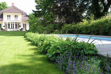 На фото: огромный участок и сад на заднем дворе в классическом стиле с полуденной тенью и настилом