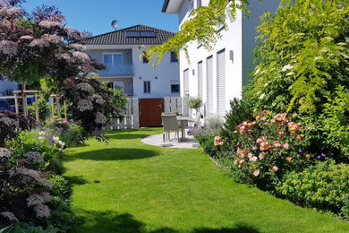 Mittelgroßer Mediterraner Garten im Sommer, neben dem Haus mit Blumenbeet, direkter Sonneneinstrahlung und Natursteinplatten in Frankfurt am Main