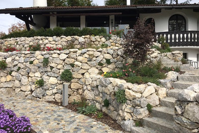 Kleine Mediterrane Gartenmauer hinter dem Haus mit Natursteinplatten in München