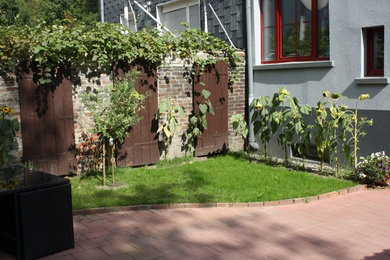 Mediterraner Garten im Innenhof mit direkter Sonneneinstrahlung, Pflastersteinen und Rasenkanten in Essen