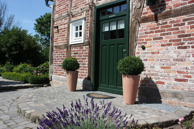 Imagen de jardín de estilo de casa de campo de tamaño medio en verano en patio delantero con jardín de macetas, exposición parcial al sol y adoquines de piedra natural
