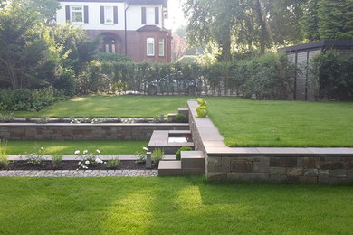Klassische Gartenmauer im Sommer, neben dem Haus mit Natursteinplatten und direkter Sonneneinstrahlung in Hamburg